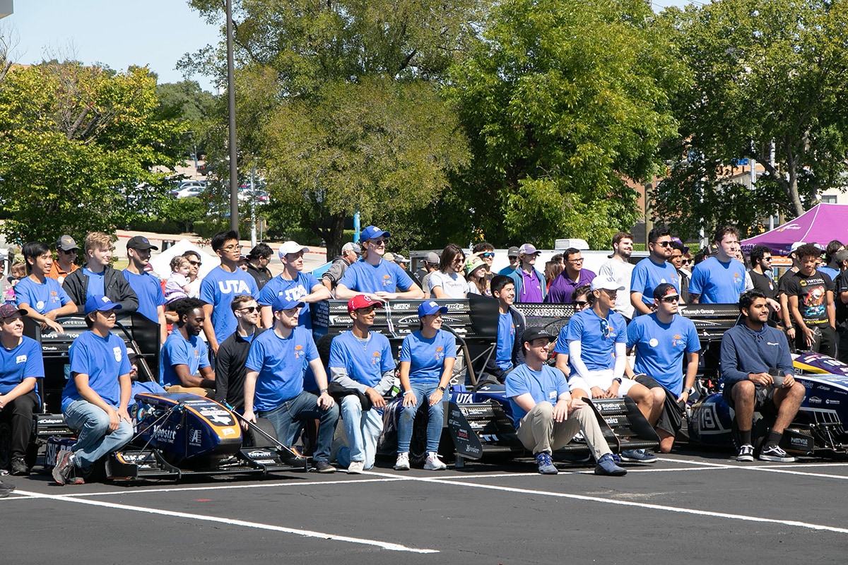 Large group of people wearing matching blue shirts posing for a picture - opens in a new tab
